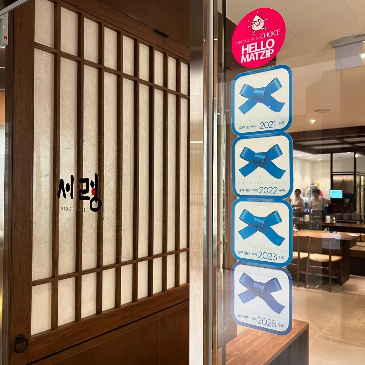 西嶺 本店 — 店名看板と受賞プレートが並ぶ入口