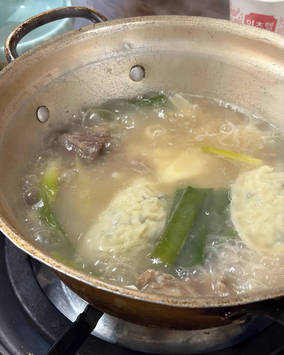 湯気立つ鍋の牛肉とネギ、すいとん