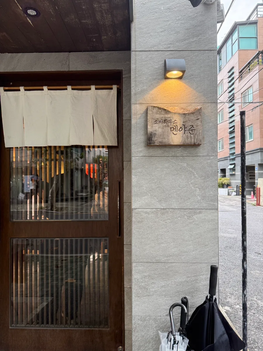 ソバハウス麺屋純 延南店 — 木の看板と暖簾のある店構え