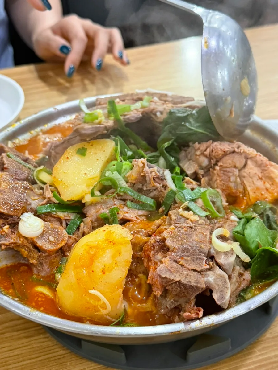 湯気立つ骨付き肉とじゃが芋の鍋