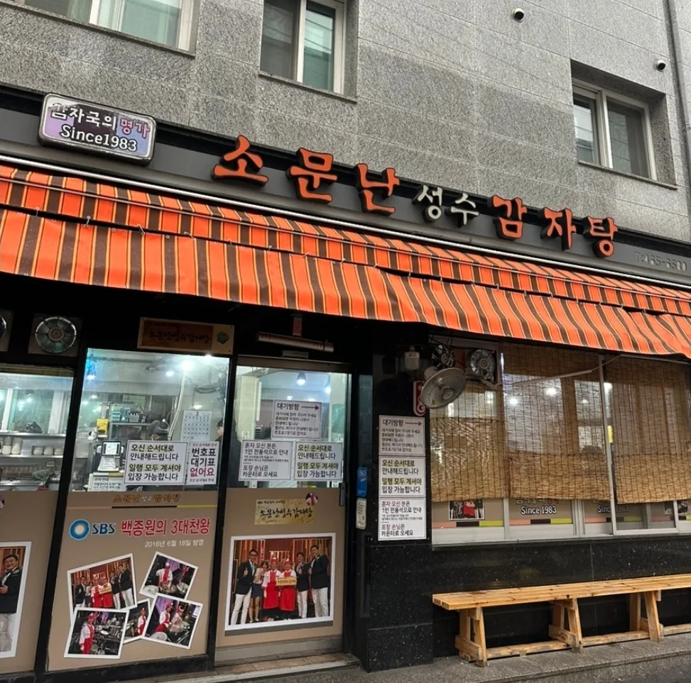 ソムンナン聖水カムジャタン — オレンジの日よけと店名看板