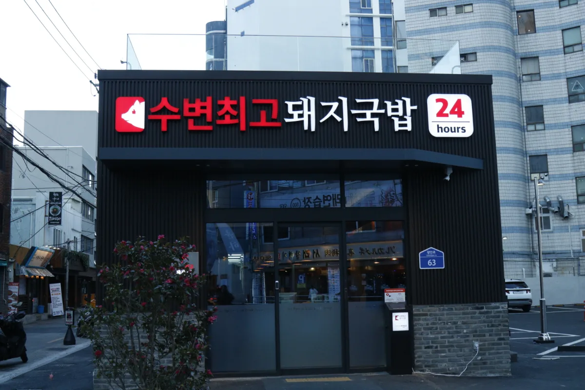水辺最高テジクッパ 広安店 — 赤と黒の看板が目立つ24時間営業の外観