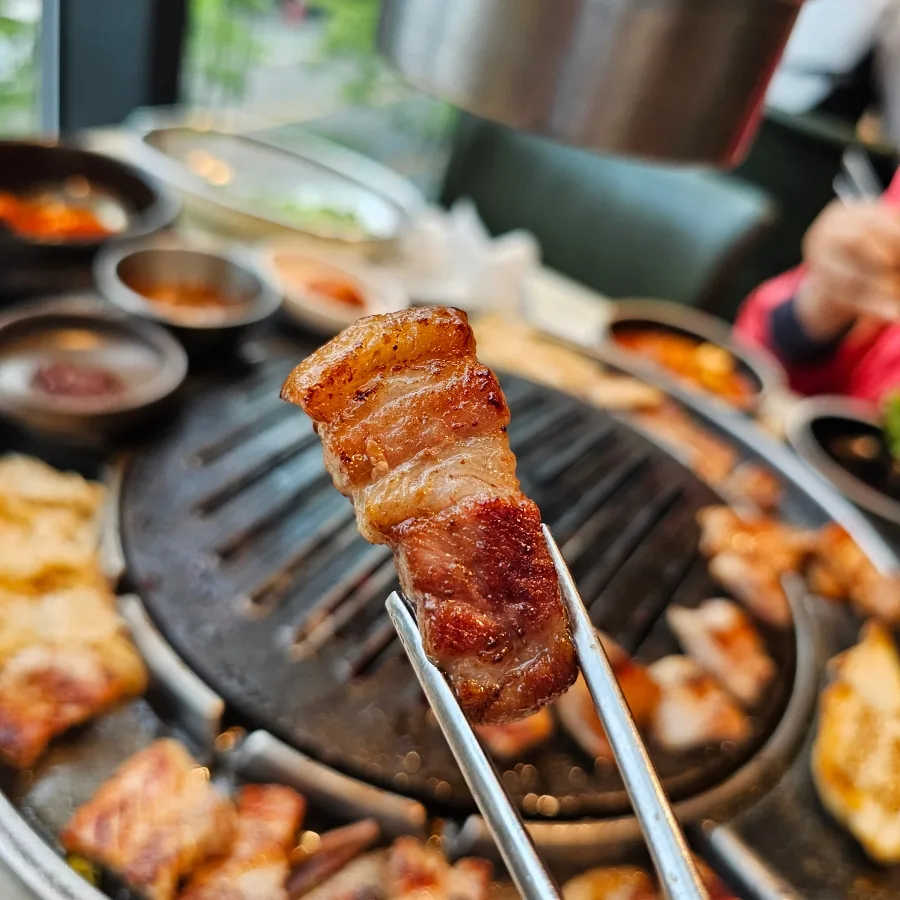 トングで持ち上げた焼きたての豚バラ