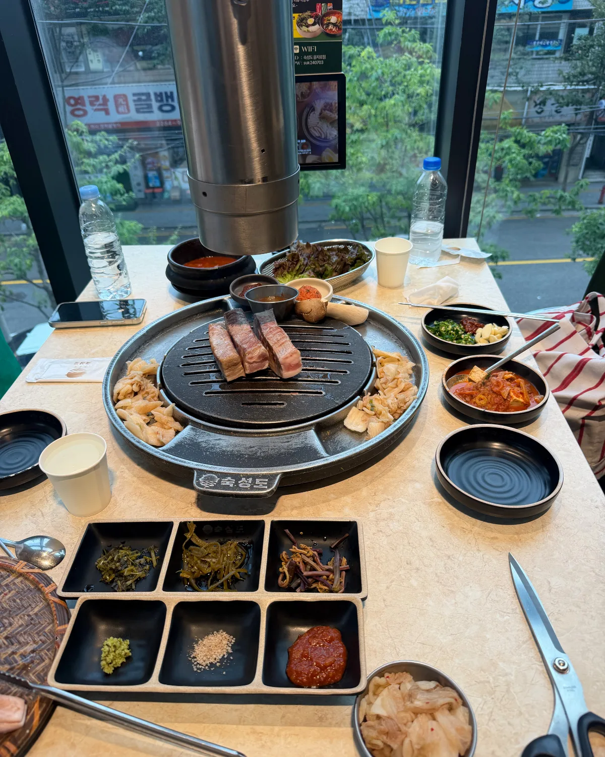 スクソンド 乙支路店 — 窓際の席に並ぶ焼肉と薬味
