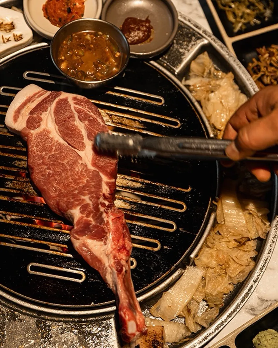熟成到 中文店 — 骨付き肉をトングで返す場面