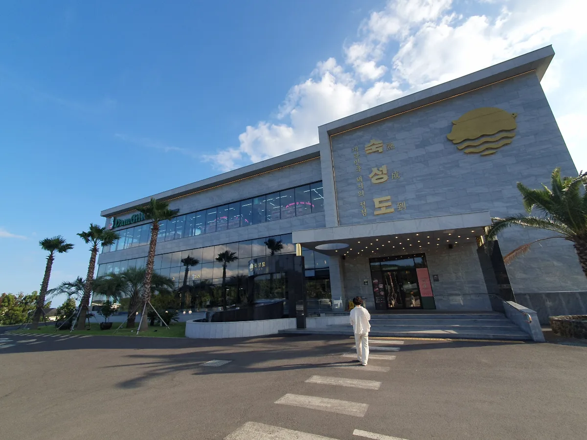 熟成到 中文店 — 看板と椰子の木が並ぶ店舗外観