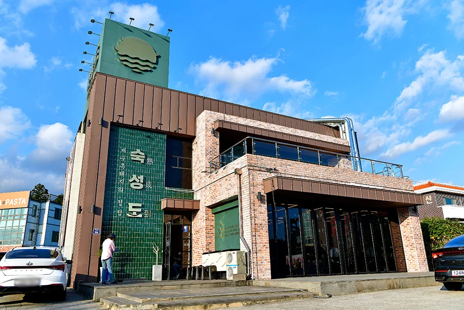 緑タイル外壁に金看板と青空