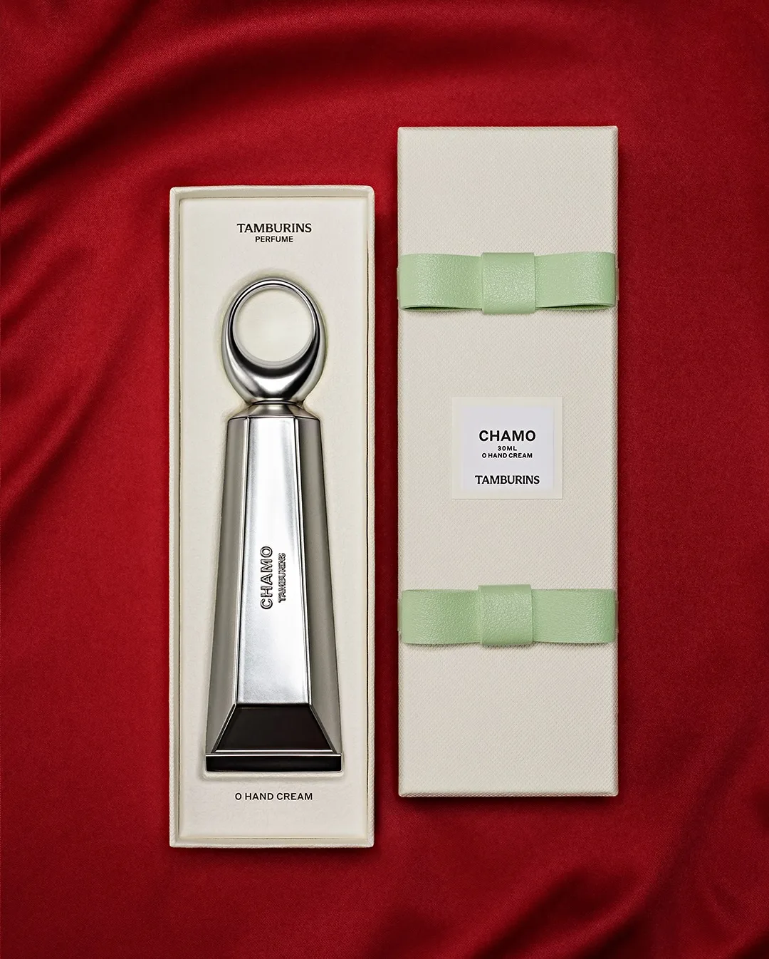TAMBURINS 聖水店 — 赤い布上の銀色クリーム容器