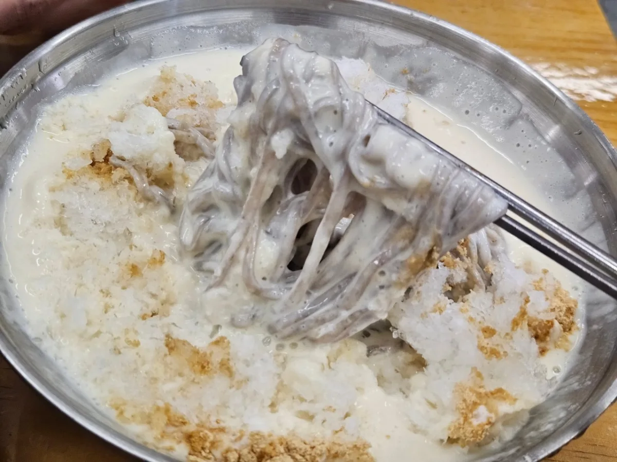 ベテランカルグクス — 氷入り豆乳麺を持ち上げる箸