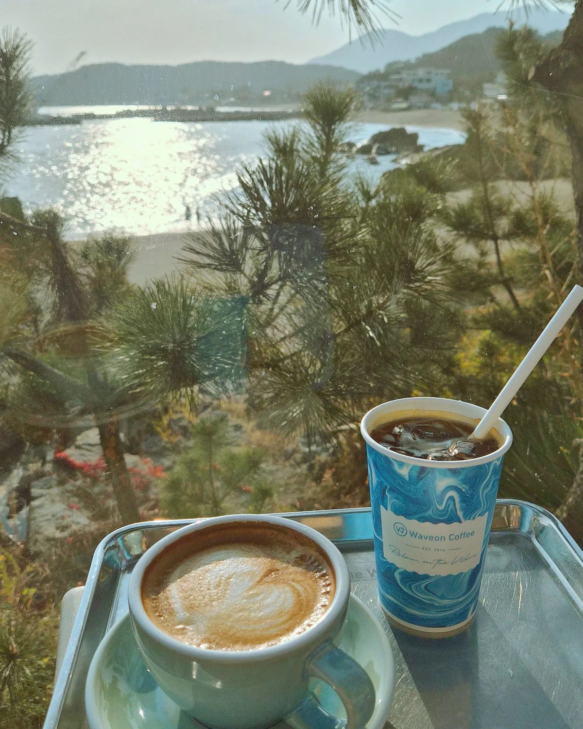 WAVEON COFFEE — 松の枝越しに見える浜辺とラテ