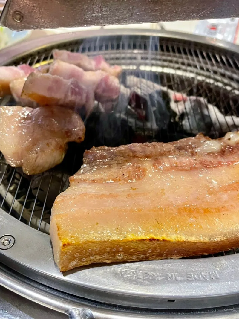 網の上で焼ける皮付きの厚い豚バラ肉