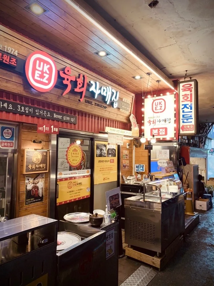 ユッケチャメチッ 本店 — 木壁と電飾看板の店内入口